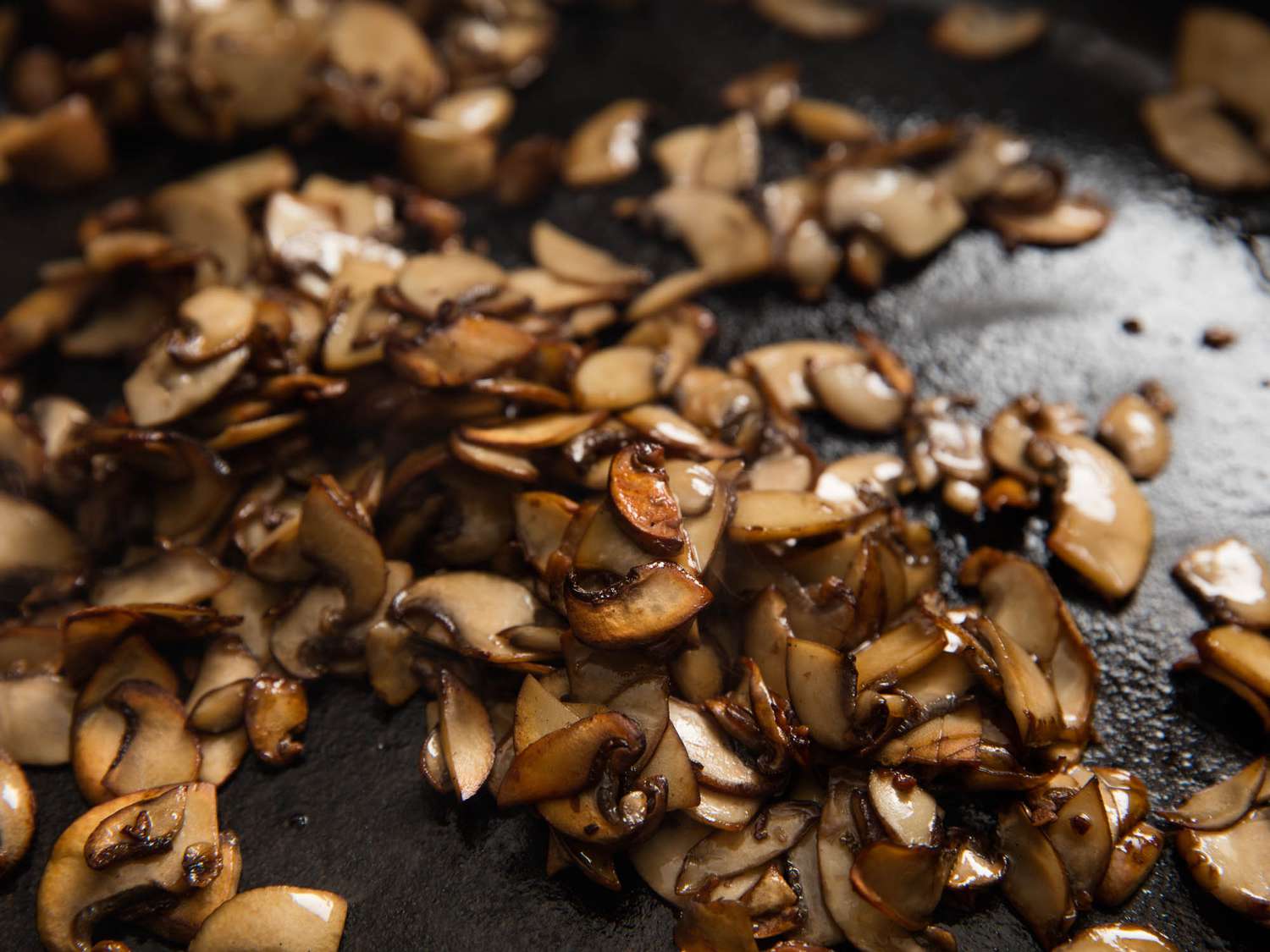 Closeup of maitake or hen-of-the-woods mushrooms being sautéed in a cast iron skillet.