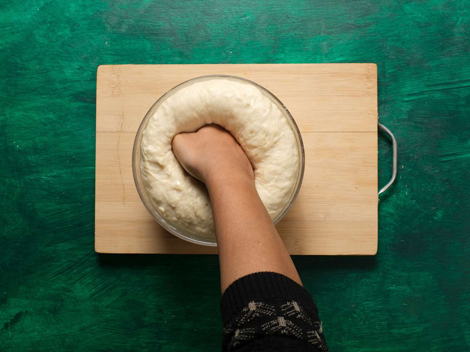 Punching dough in bowl 