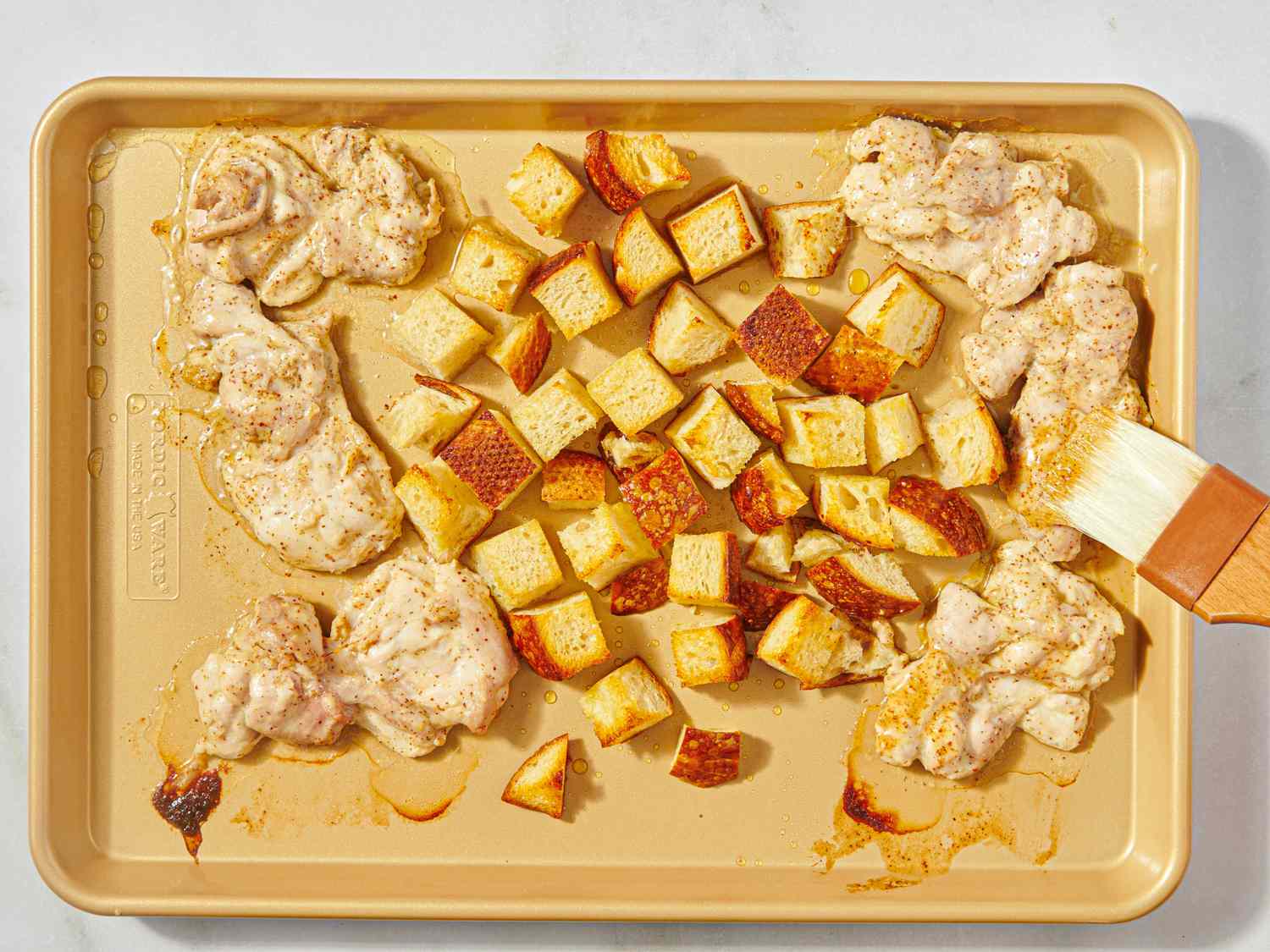 A baking sheet with cooked chicken thighs and roasted diced potatoes