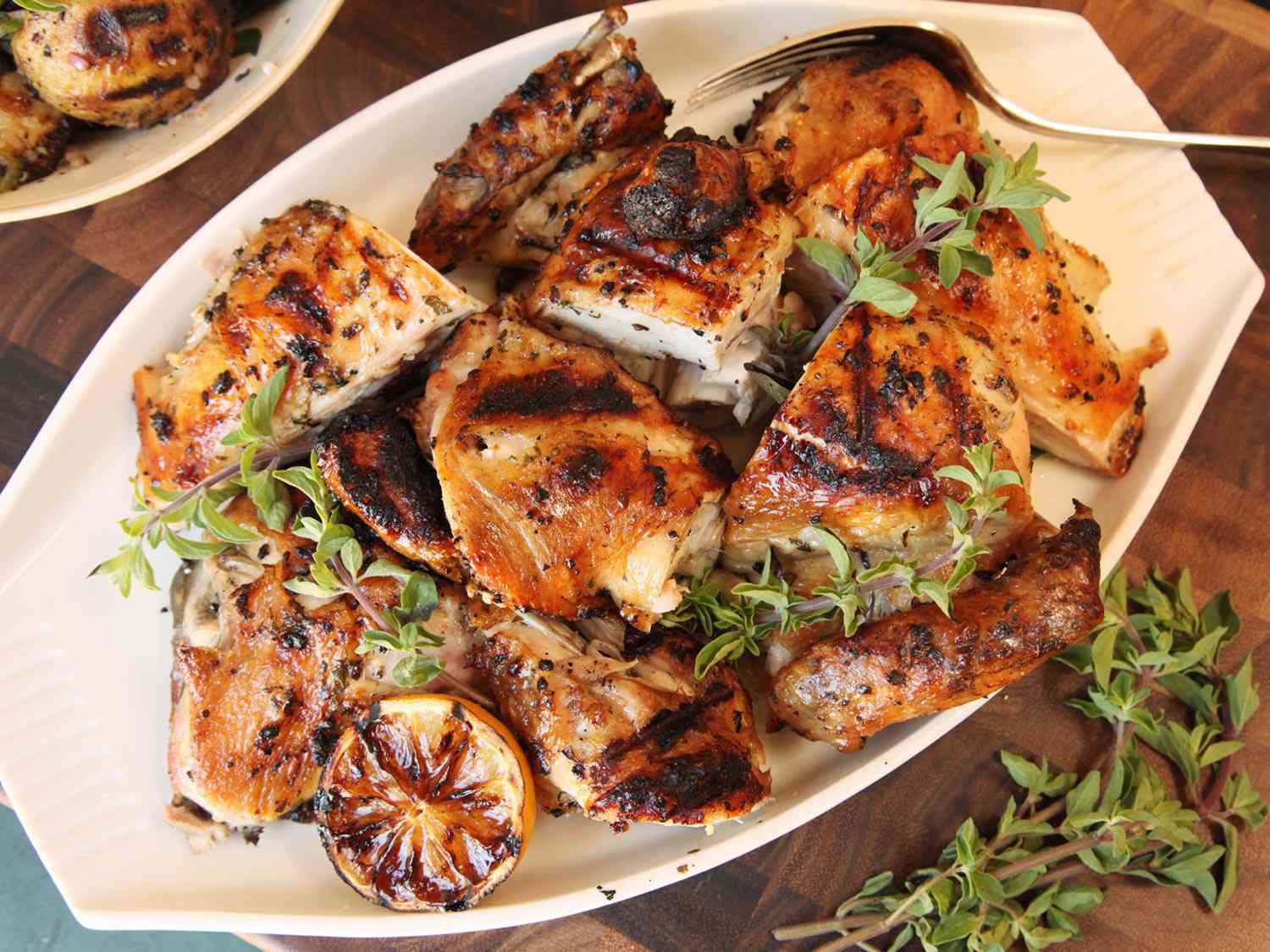 Pieces of Greek-style grilled chicken on a platter with serving fork