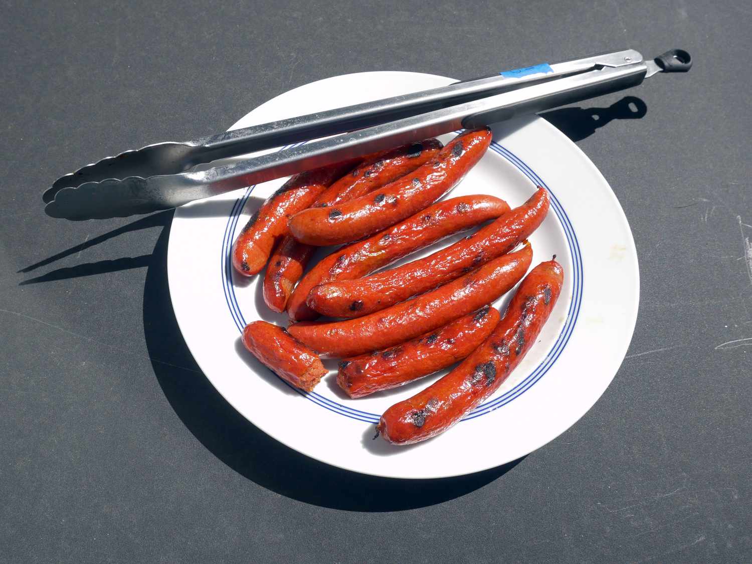 the oxo tongs resting on a plate of grilled hot dogs