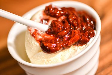 A bowl of vanilla ice cream topped with strawberry balsamic sauce.