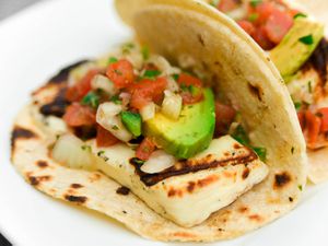 close-up of charred grilling cheese soft taco with avocado and pico de gallo