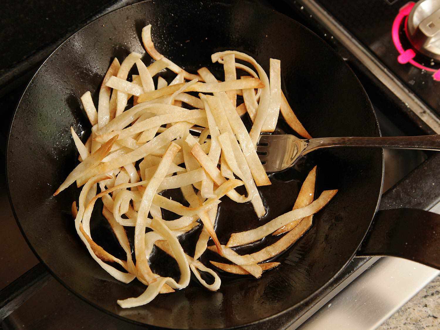 Tortilla strips are fried in a small skillet.