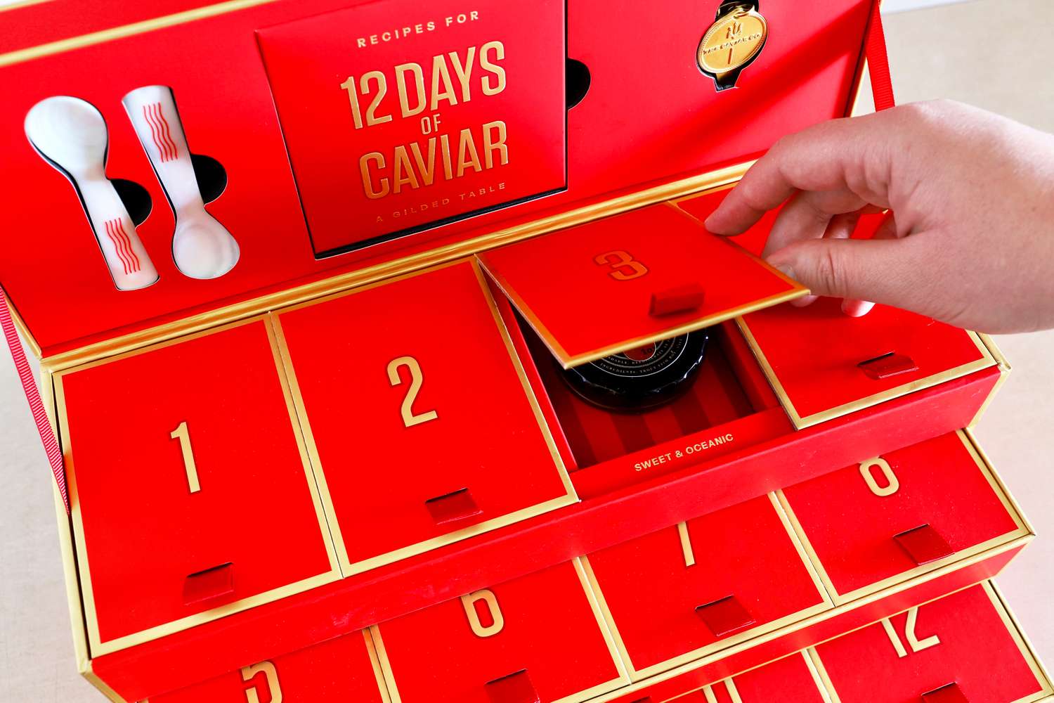 A hand opening one of the doors of the Caviar Co 12 Days of Caviar Advent calendar