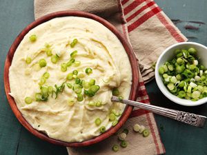 a serving bowl of mashed potatoes with some thinly sliced scallions