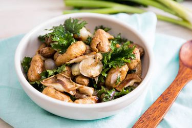 A small white bowl of Roasted Potato and Shallot Salad With Marinated Mushrooms and Kale.
