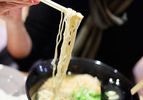 Ramen being pulled from a bowl with chopsticks