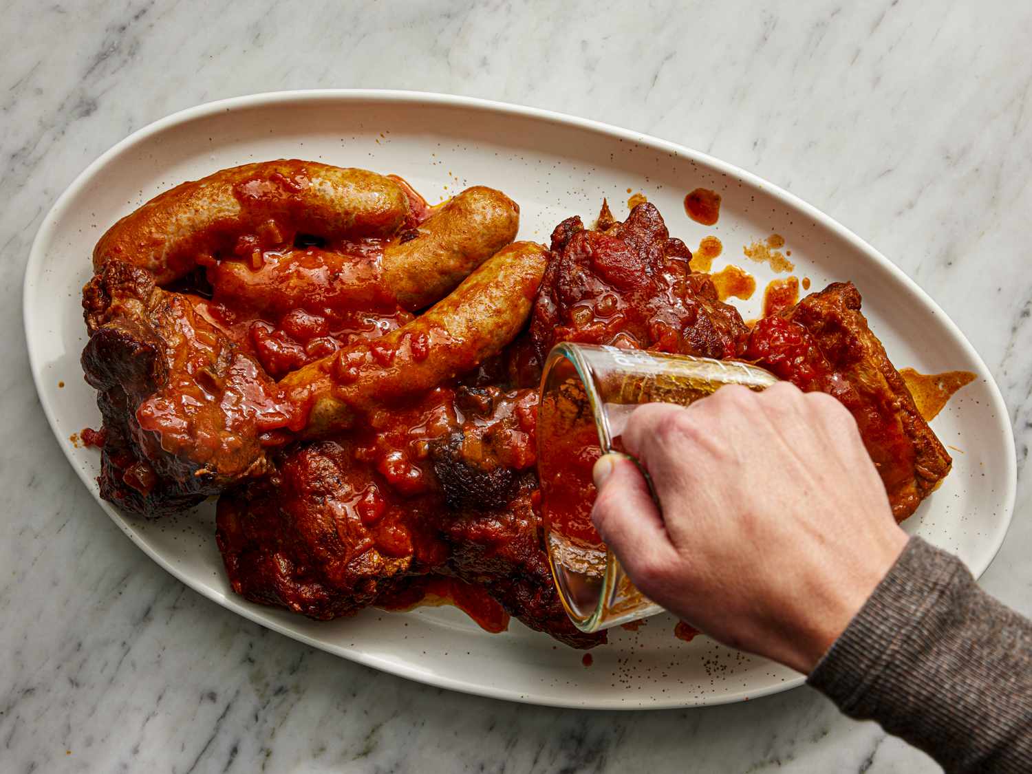 Pouring sauce over meat removed from dutch oven on a platter