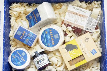 An assortment of gourmet cheese and other food items arranged in a gift box
