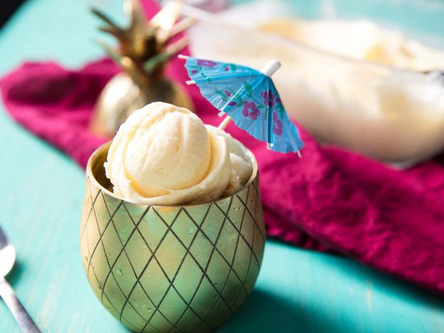 A scoop of homemade pineapple ice cream decorated with a cocktail umbrella.