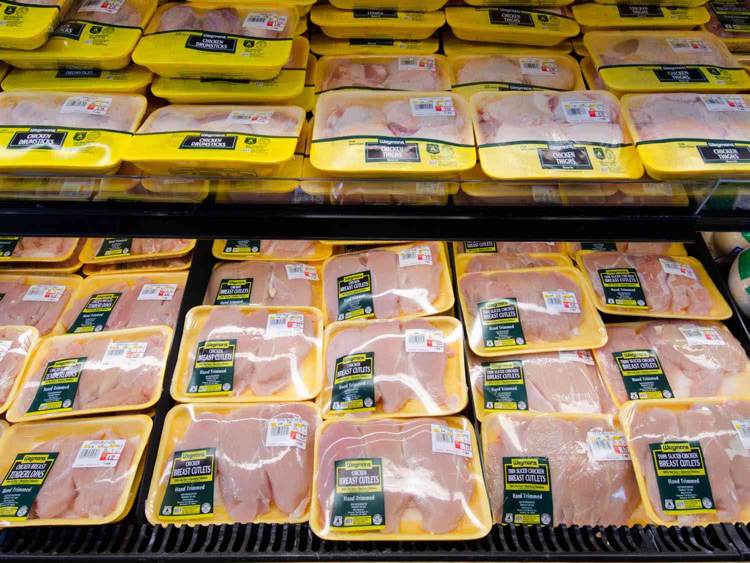 Packages of chicken in a meat case at a grocery store.