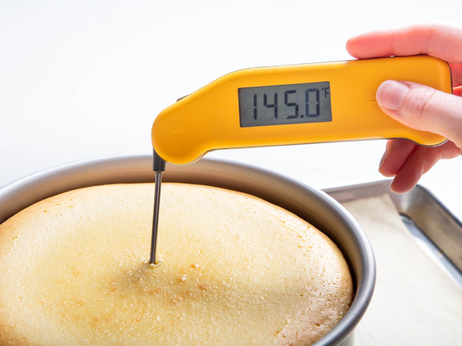 The internal temperature of the finished cheesecake is measured with an instant read thermometer, which reads 145 degrees Fahrenheit.