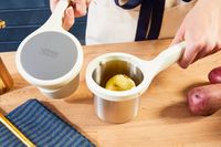 A half of a peeled potato in the hopper of the Joseph Joseph potato ricer.