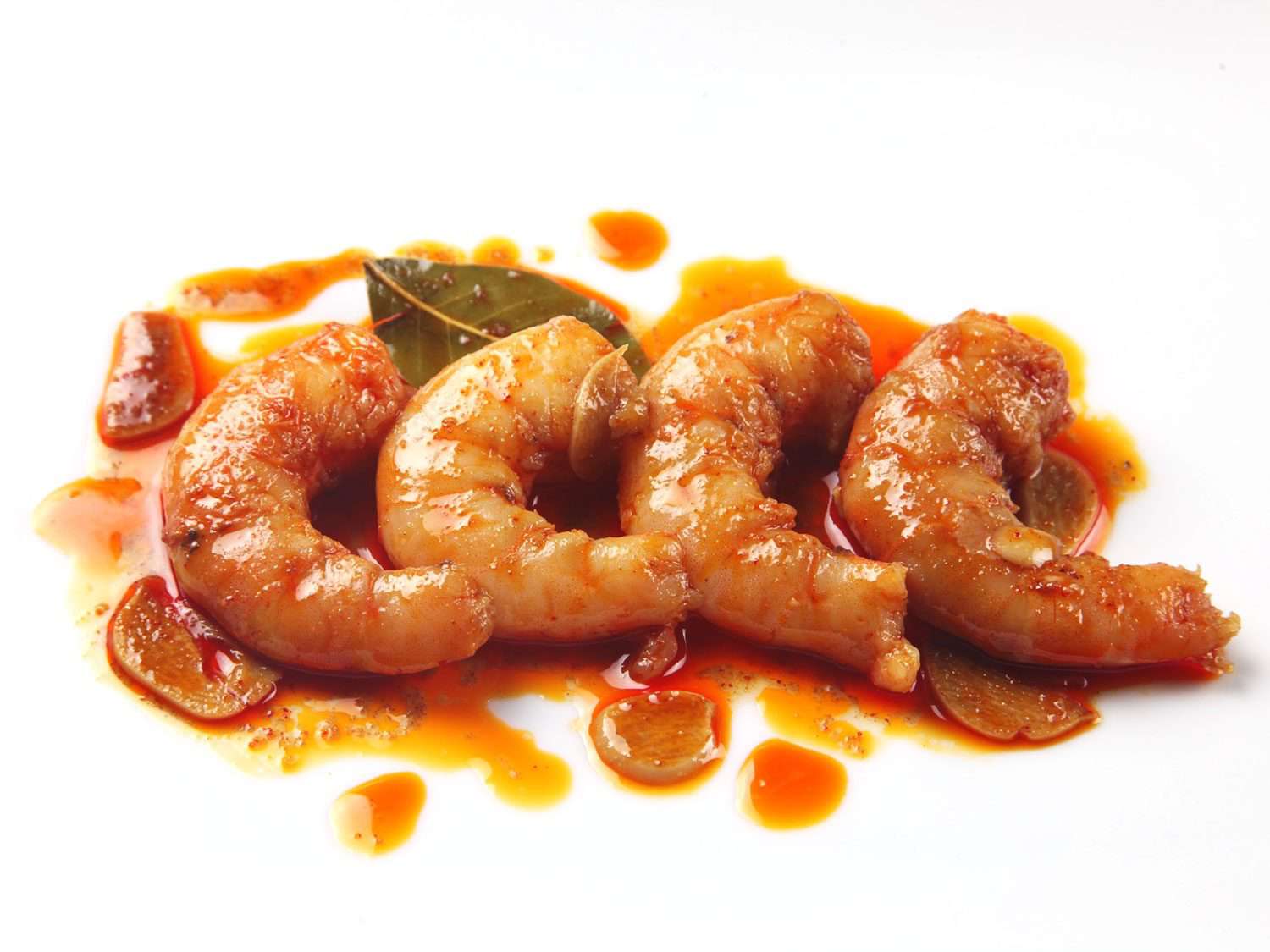Four shrimp cooked sous vide with Garlic, Sherry, and Smoked Paprika, lined up in a row in their juices
