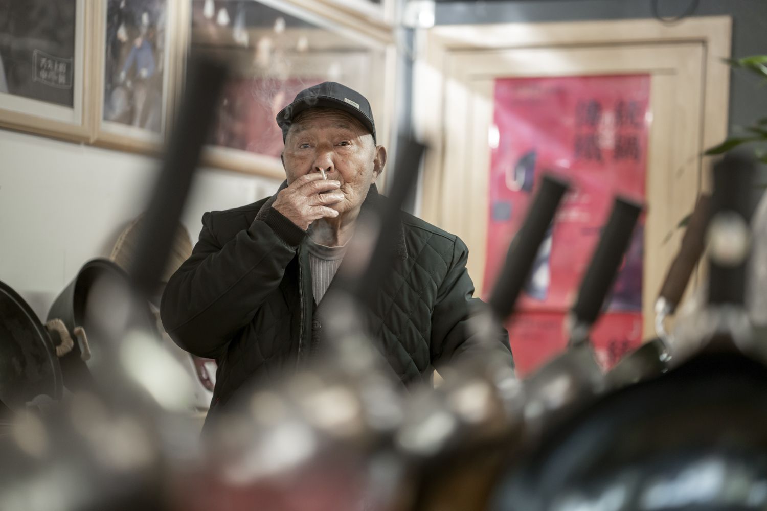 Wang Lifang smoking a cigarette in the display shop for Zhen San Huan woks