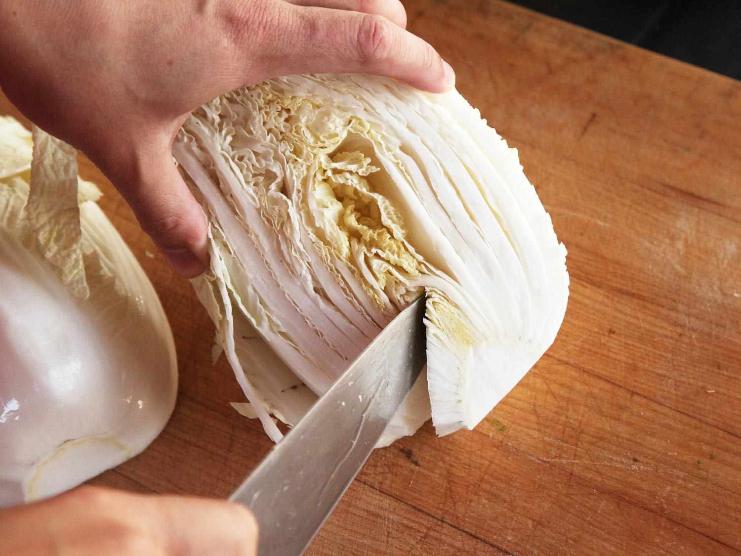 Cutting out the core of a head of Napa cabbage with a chef's knife. 