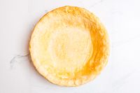 An overhead view of a baked pie crust on a marble sruface