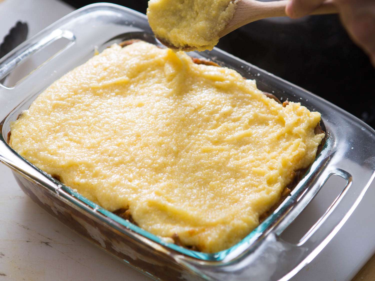 A top layer of polenta is spread over the fillings.