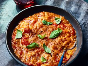 Bowl of Pappa Al Pomodoro in a black bowl on dark blue surface, with dark dyed napkin and a glass of red wine 