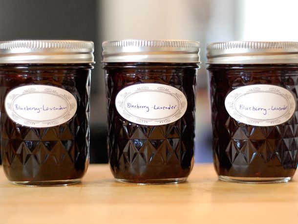 Profile view of three half-pint canning jars filled with lavender blueberry jam.