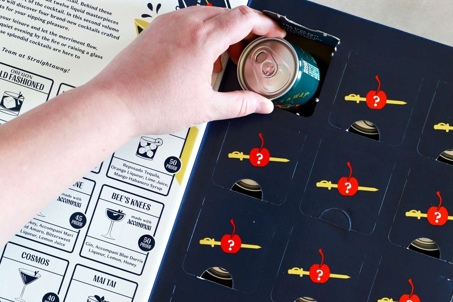 The Straightaway 12 Days of Cocktails with one door opened, with a hand pulling a cocktail can out
