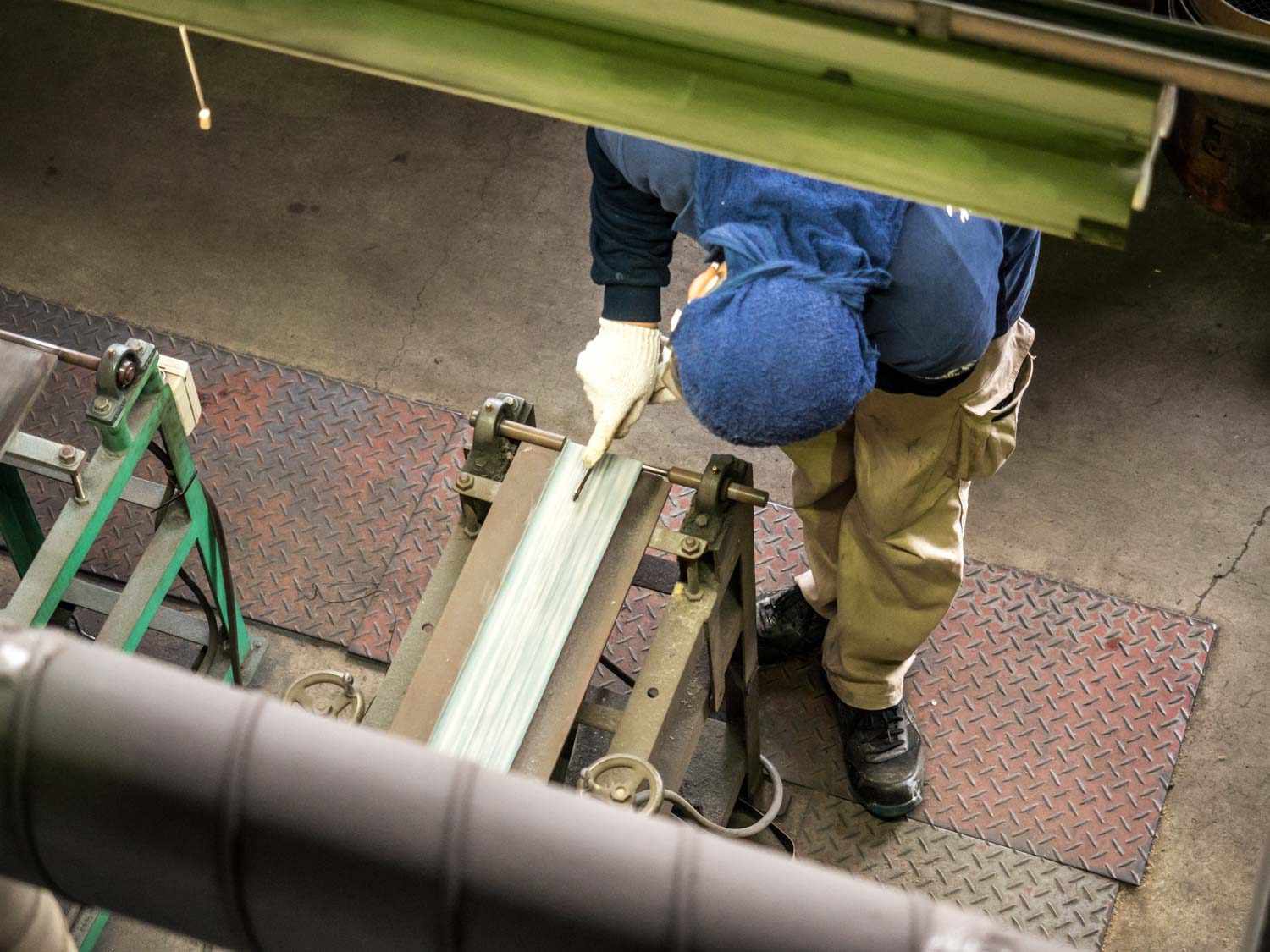 Overehad view of a bladesmith at work over a belt grinder.