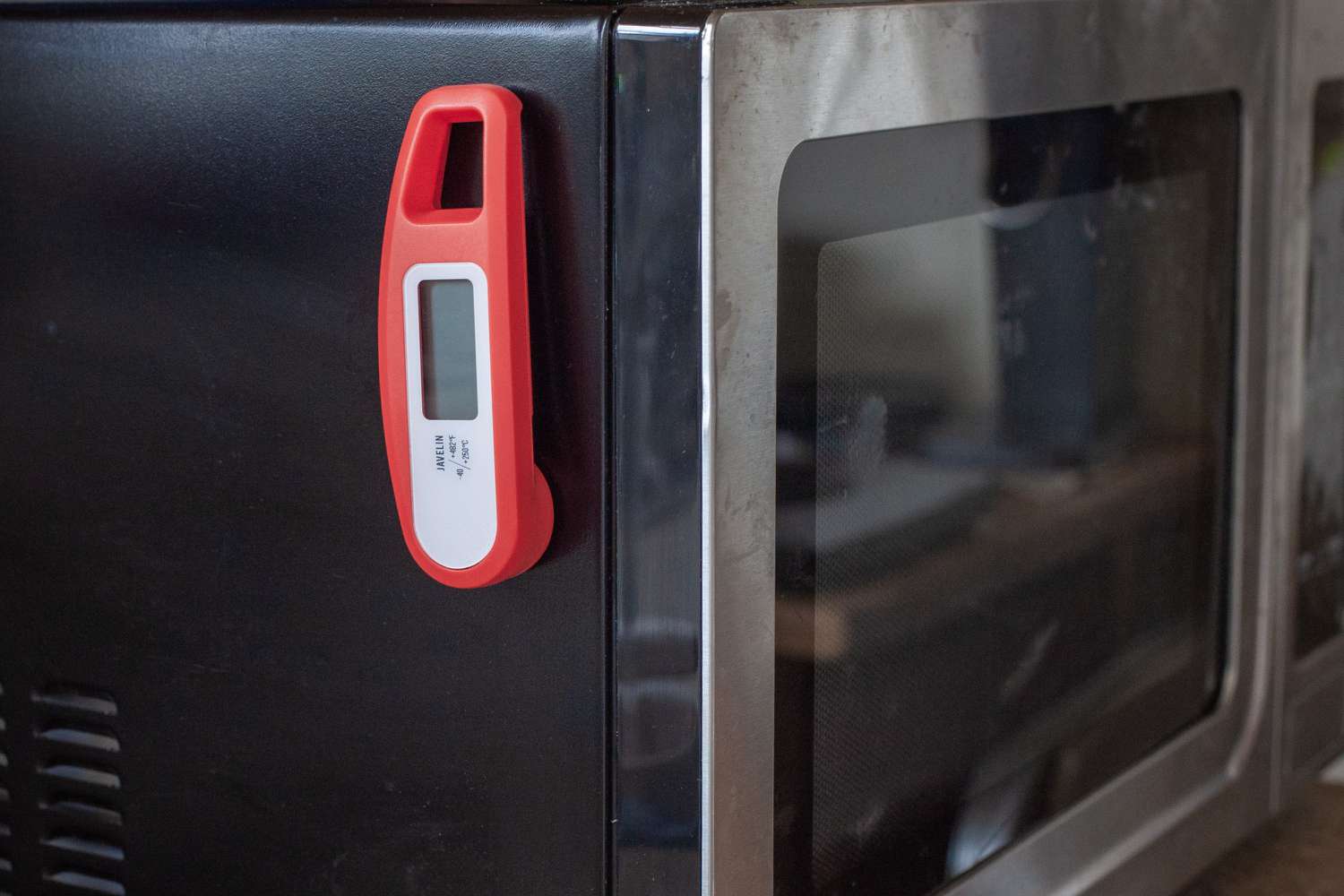 A magnetic instant-read thermometer attached to the of a microwave.