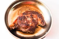 A cooked steak in a frying pan