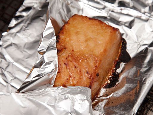 Miso-glazed salmon fillet on an aluminium foil-lined tray; its corner being covered by the foil to prevent excessive browning. 