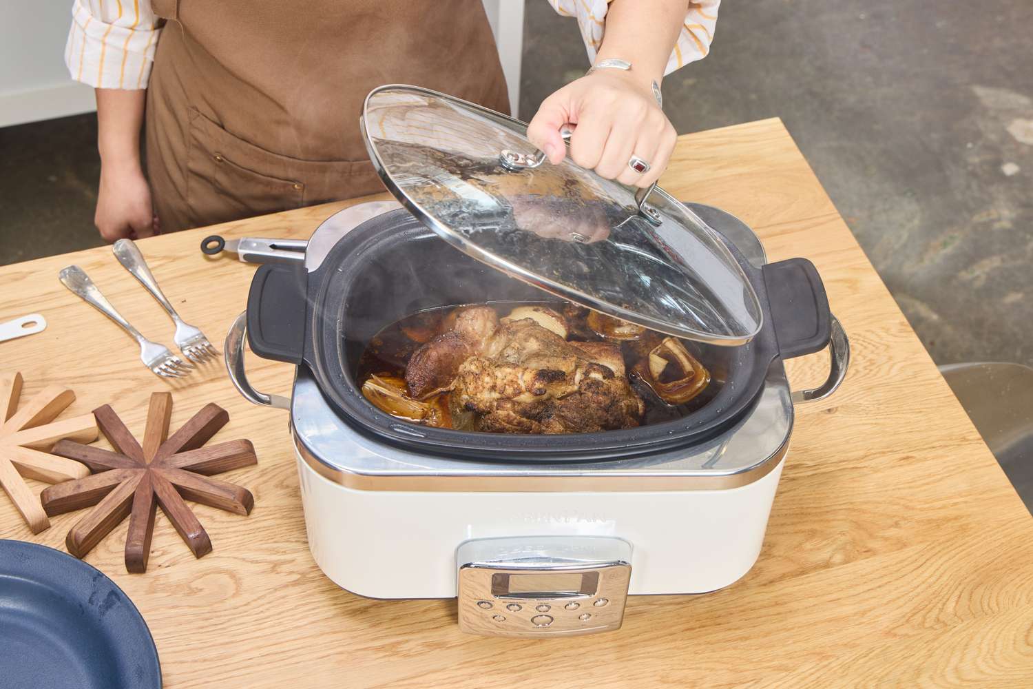 A person removes the lid of the GreenPan Elite 6-Quart Slow Cooker
