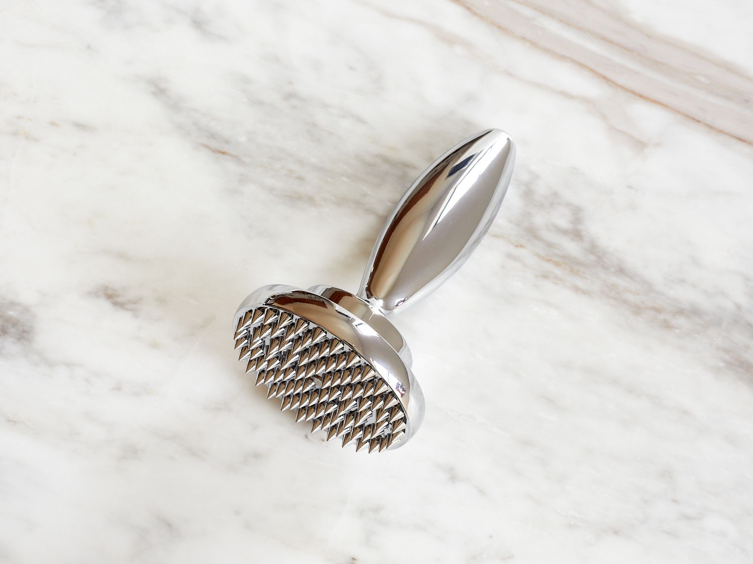 A spiked metal object on a marble surface featuring a rounded end and a handle