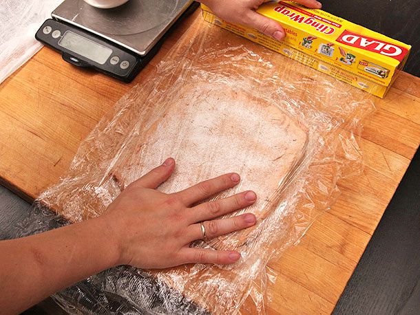 Wrapping flattened foie gras in plastic wrap, prepared to be rolled. 