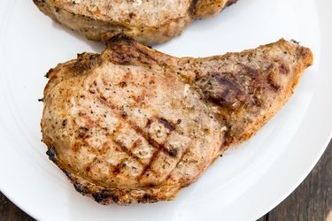 A grilled pork chop on a plate with grill marks.