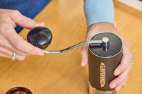 A person turns the crank on the top of the Comandante C40 Nitro Blade Grinder