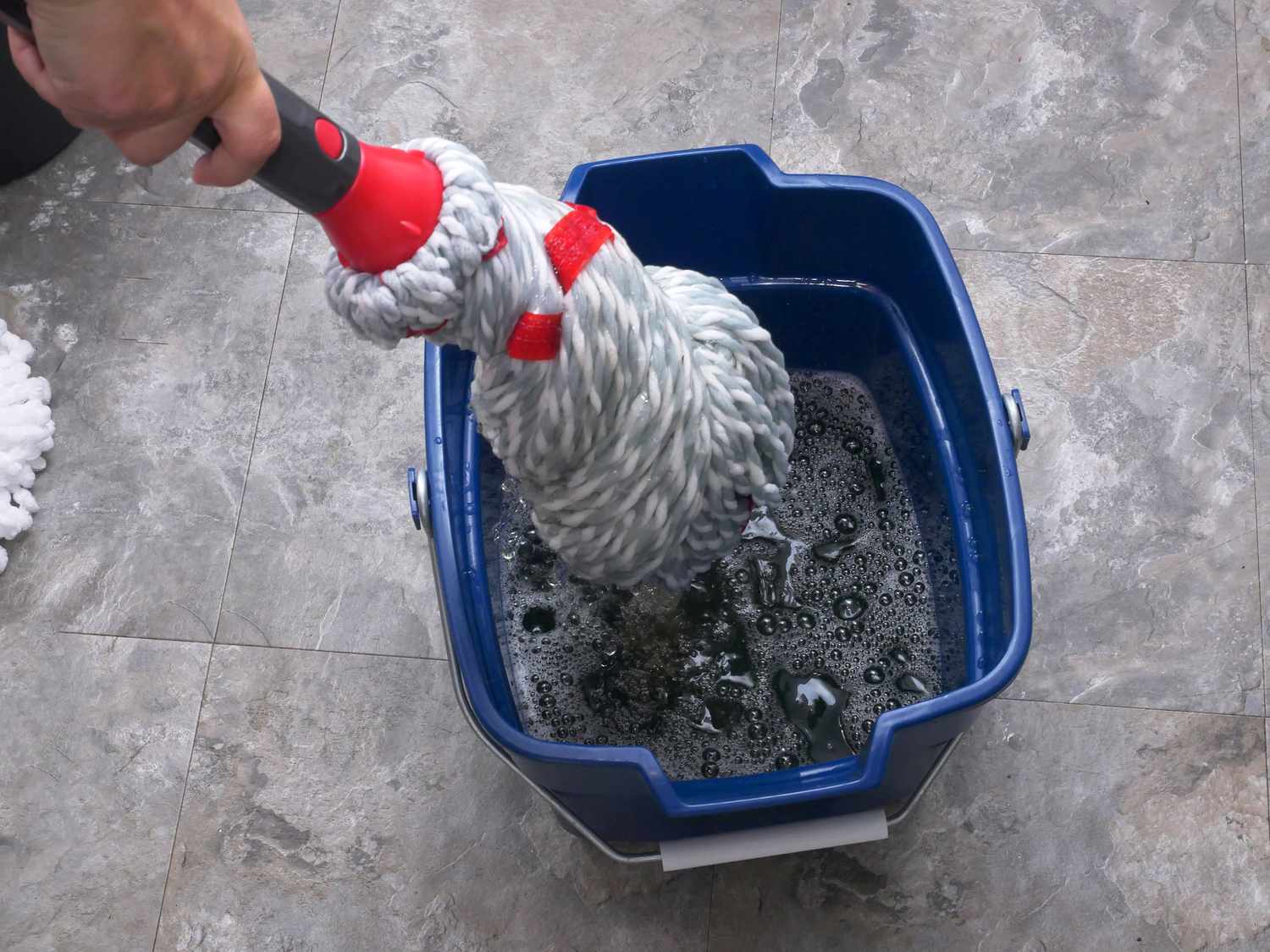 wringing out the rubbermaid mop into a blue bucket 