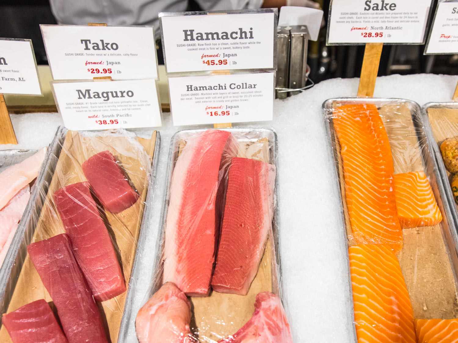 Sushi-grade raw fish displayed on ice at a market.