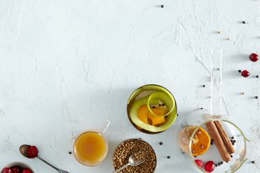 An overhead view of an Eve's addiction cocktail, surrounded by fruit and whole spices.