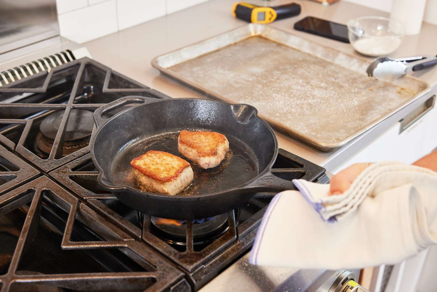 A person searing pork in a cast iron skillet.