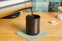 Coffee being poured into a Fellow coffee mug.