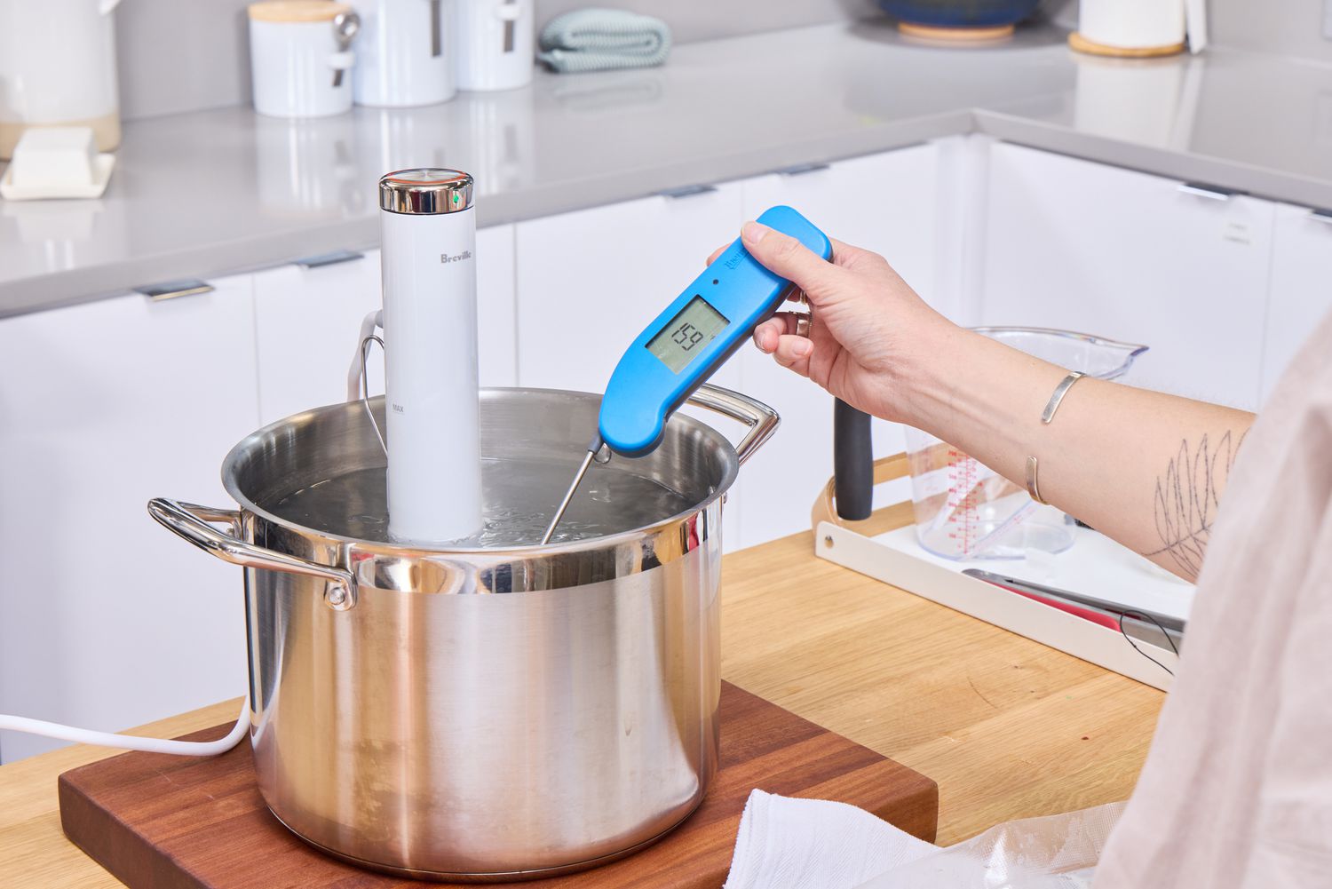 A person measures the temperature of water while using the Breville Joule Turbo Sous Vide