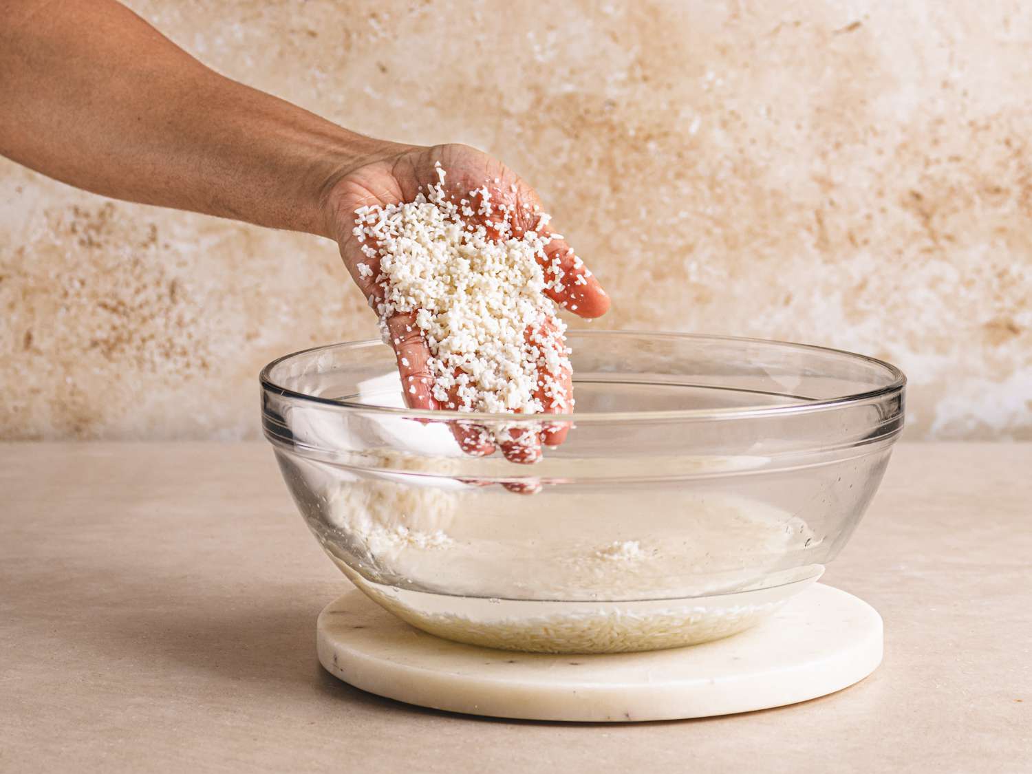 A hand with broken down rice after soaking for 8 hours