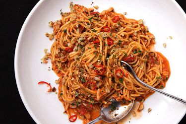 Overhead view of pasta with crab, tomato, and chiles, served in a large white bowl.