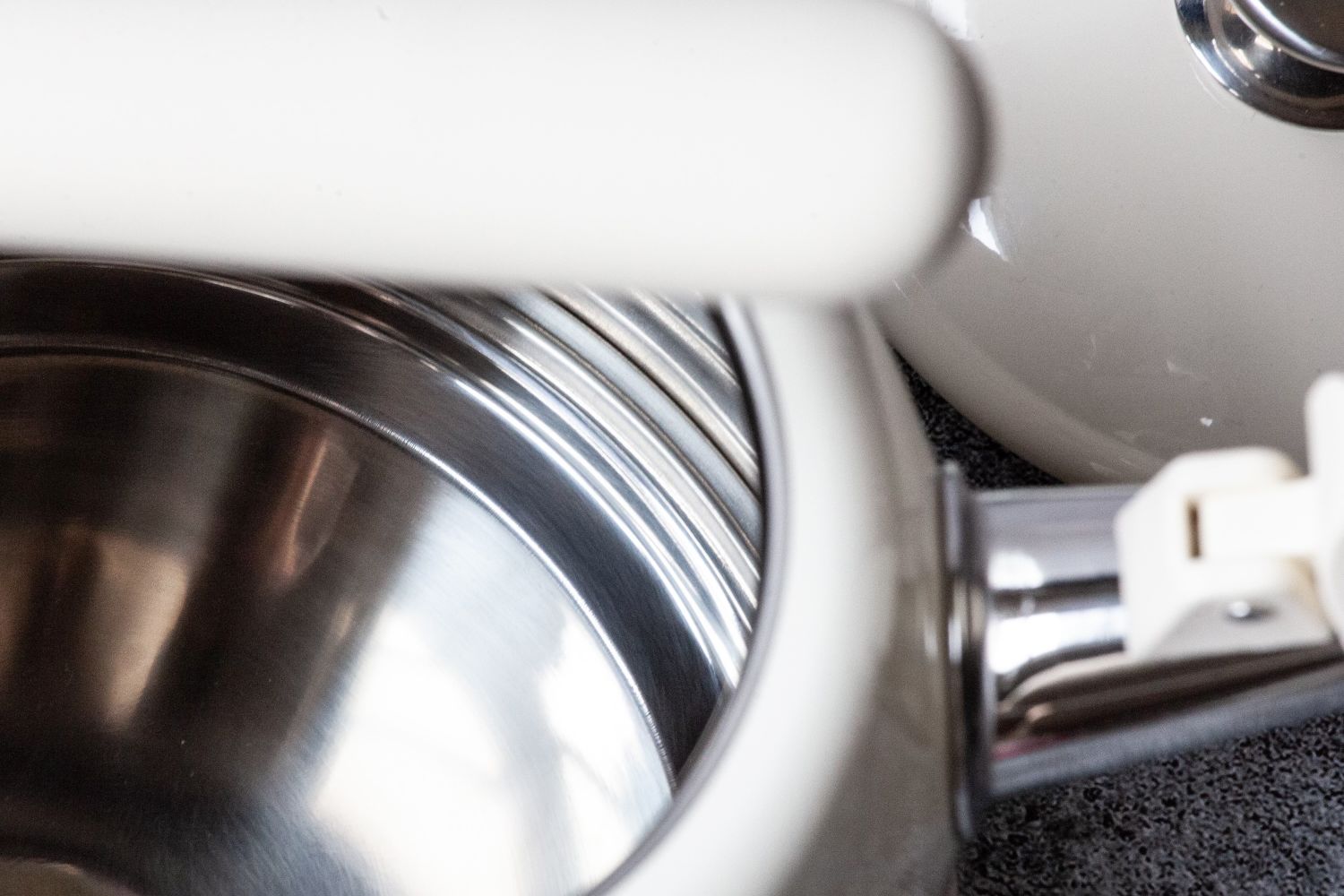 Closeup of a stainless steel cooking pot and a white handle