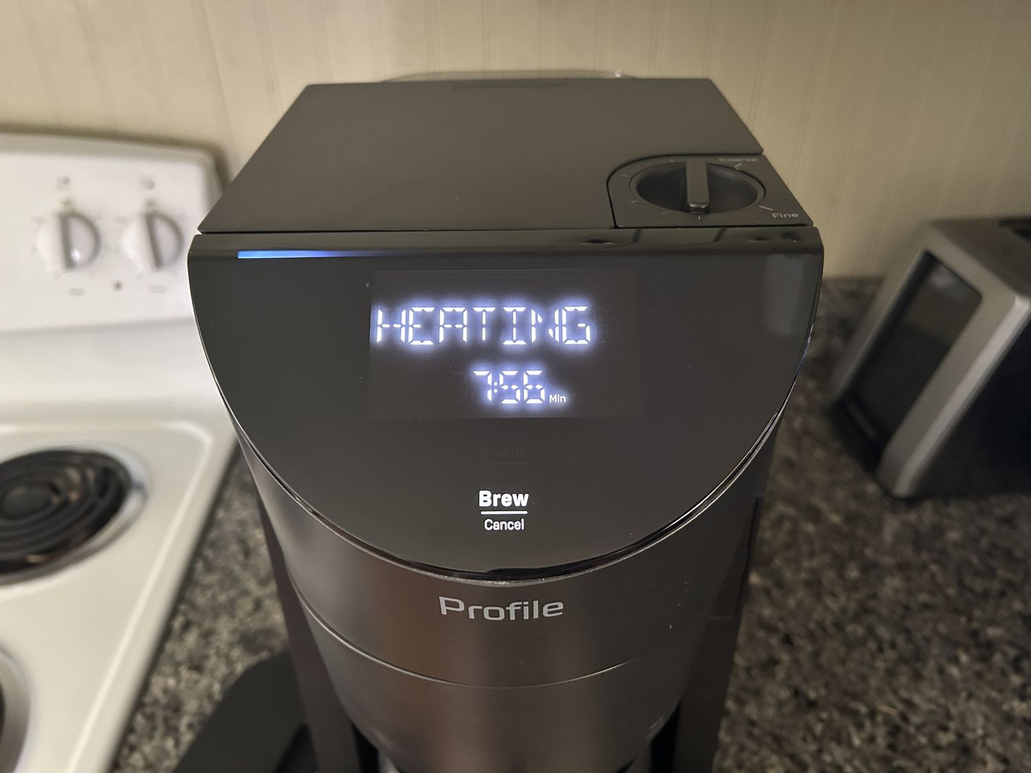 The digital display on the GE Smart Grind coffee maker showing the word "heating."