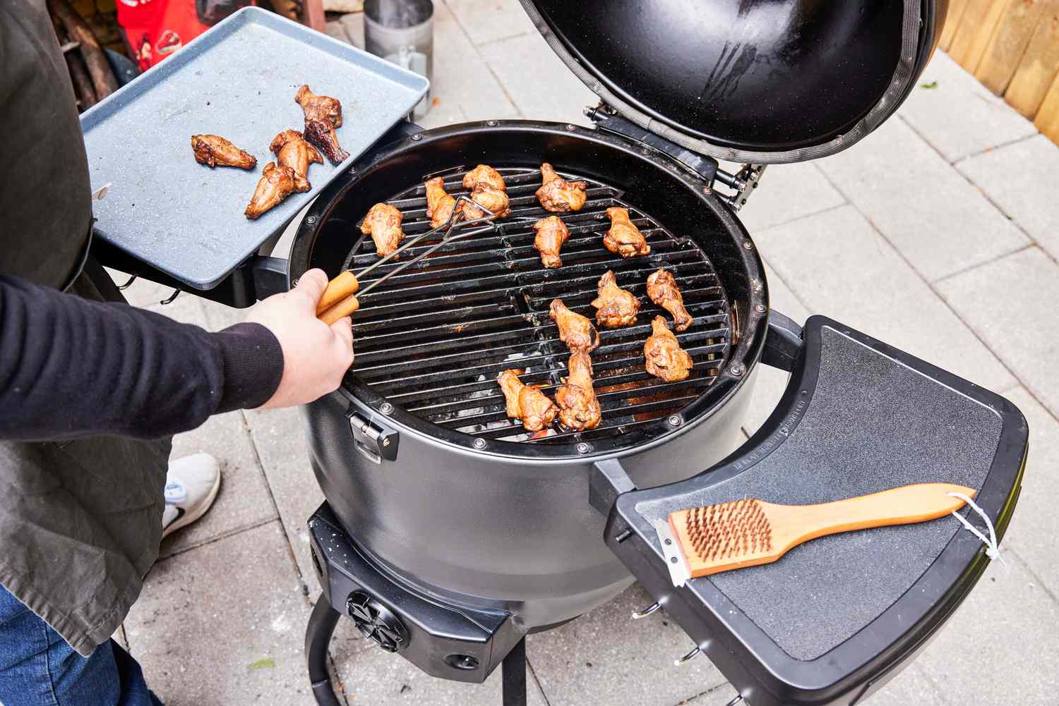 A person cooks chicken in the Broil King Keg Kamado Charcoal Grill