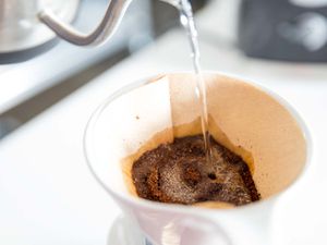 A goose-neck kettle is used to precisely wet coffee grounds, or "bloom" them, before brewing.