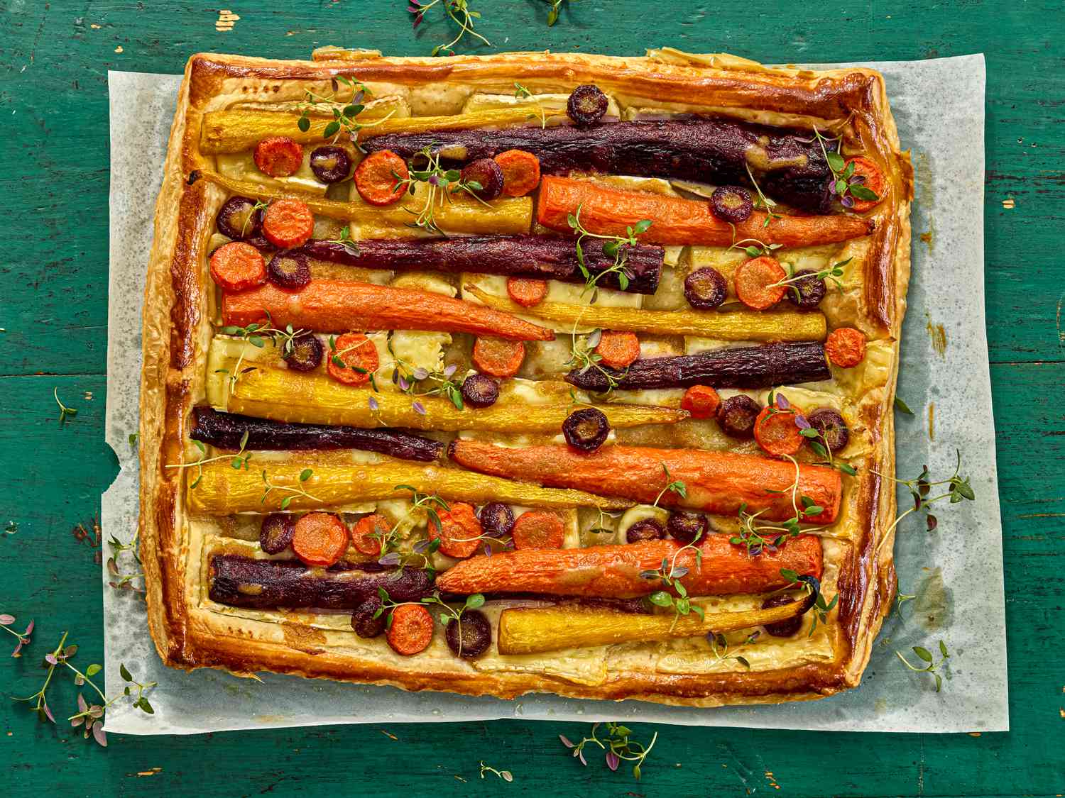 carrot tart on a sheet of parchment paper on a green wooden surface 