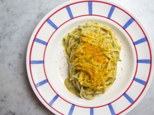 Pasta con la Bottarga resting on a white, red, and blue patterned plate.