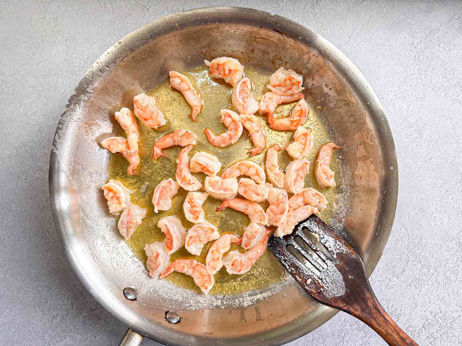 Shrimp cooking in a pan with a metal spatula on the side